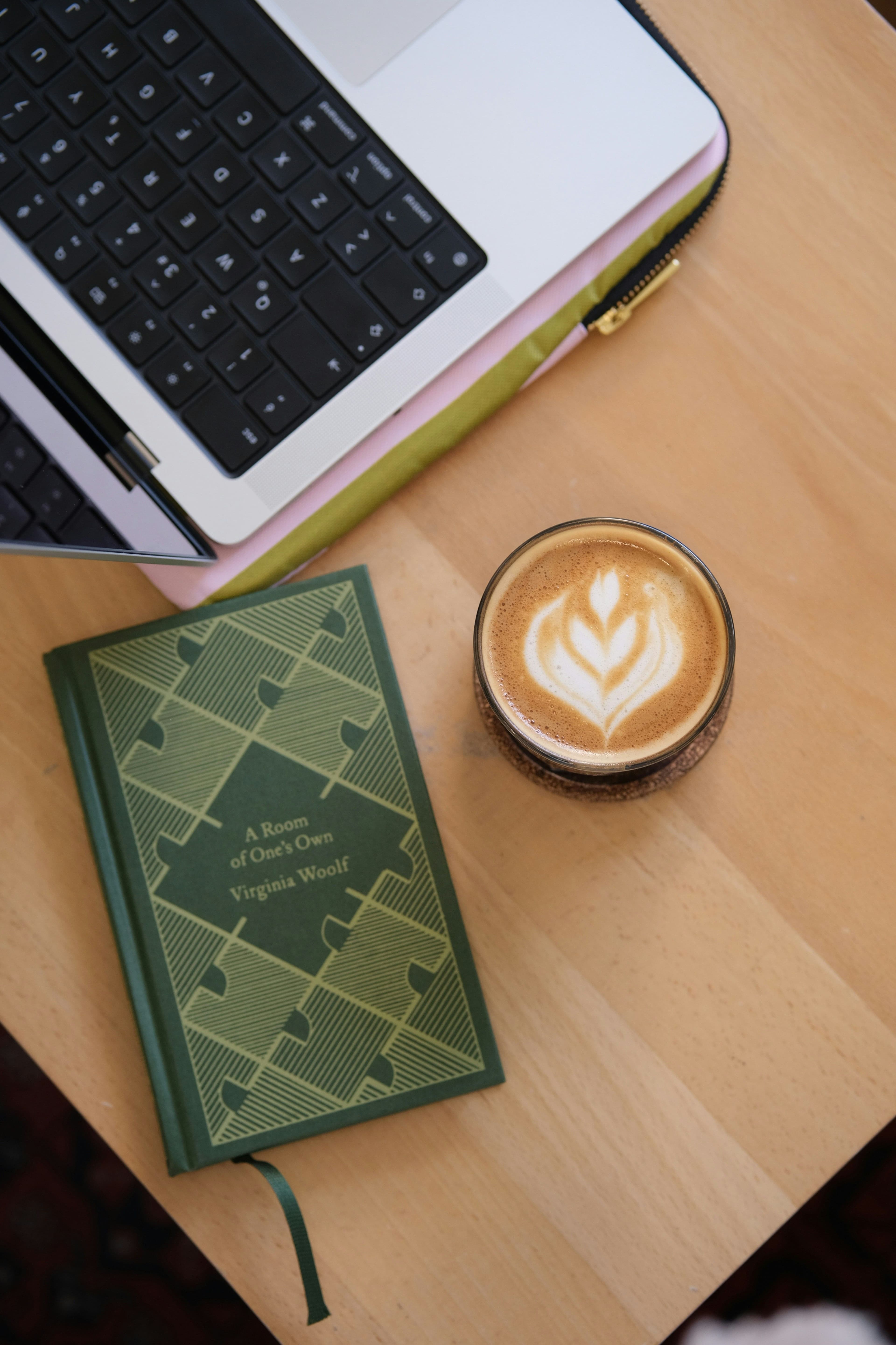 A laptop, book, and latte on a wooden desk—a quiet moment to design a family photo book.