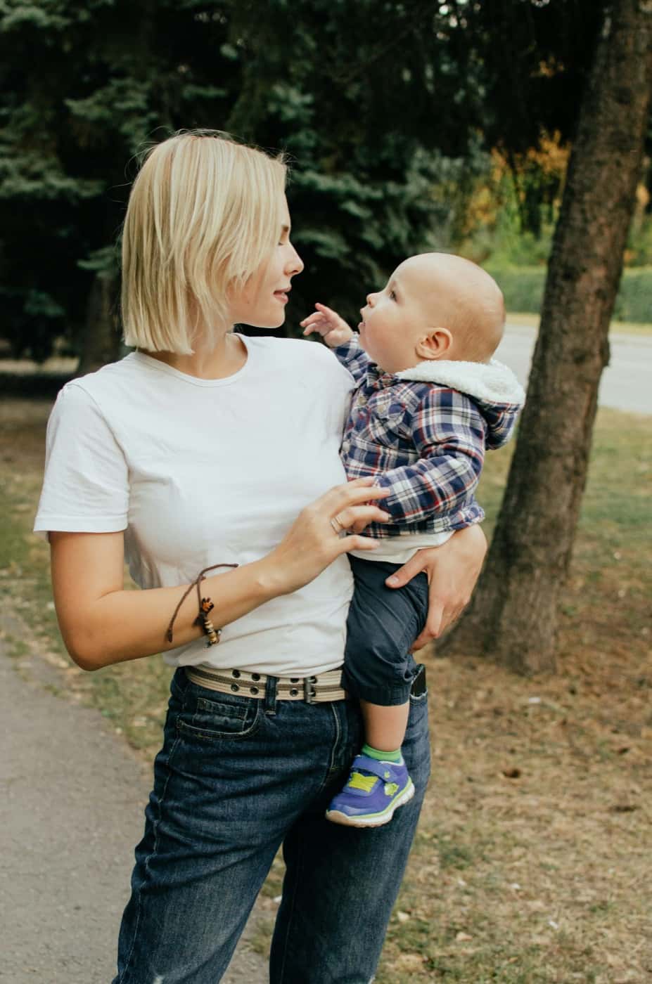 A parent holding a baby outside in soft afternoon light.
