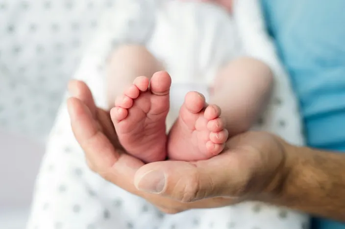 A newborn's feet resting gently in an adult's hands.
